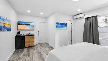 A modern hotel room with a bed, a desk with a computer, and artwork on the walls.