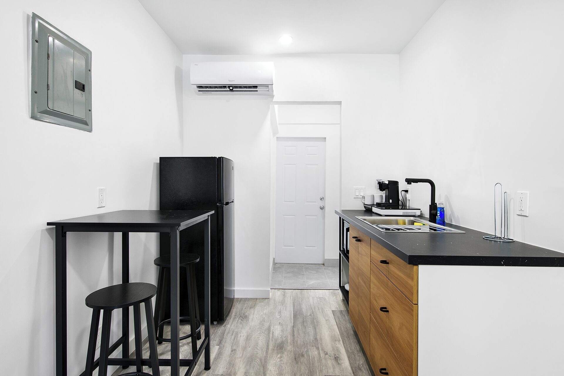 A compact kitchen with a black countertop, a coffee machine, and a sink.