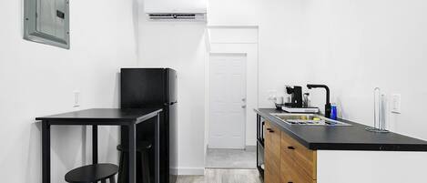 A compact kitchen with a black countertop, a coffee machine, and a sink.