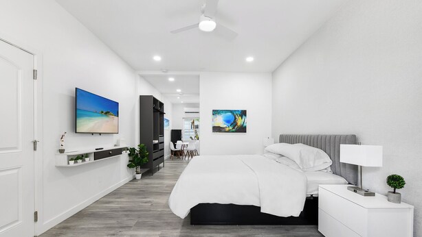 Ein modernes Schlafzimmer mit Bett, Nachttisch und Deckenventilator.
