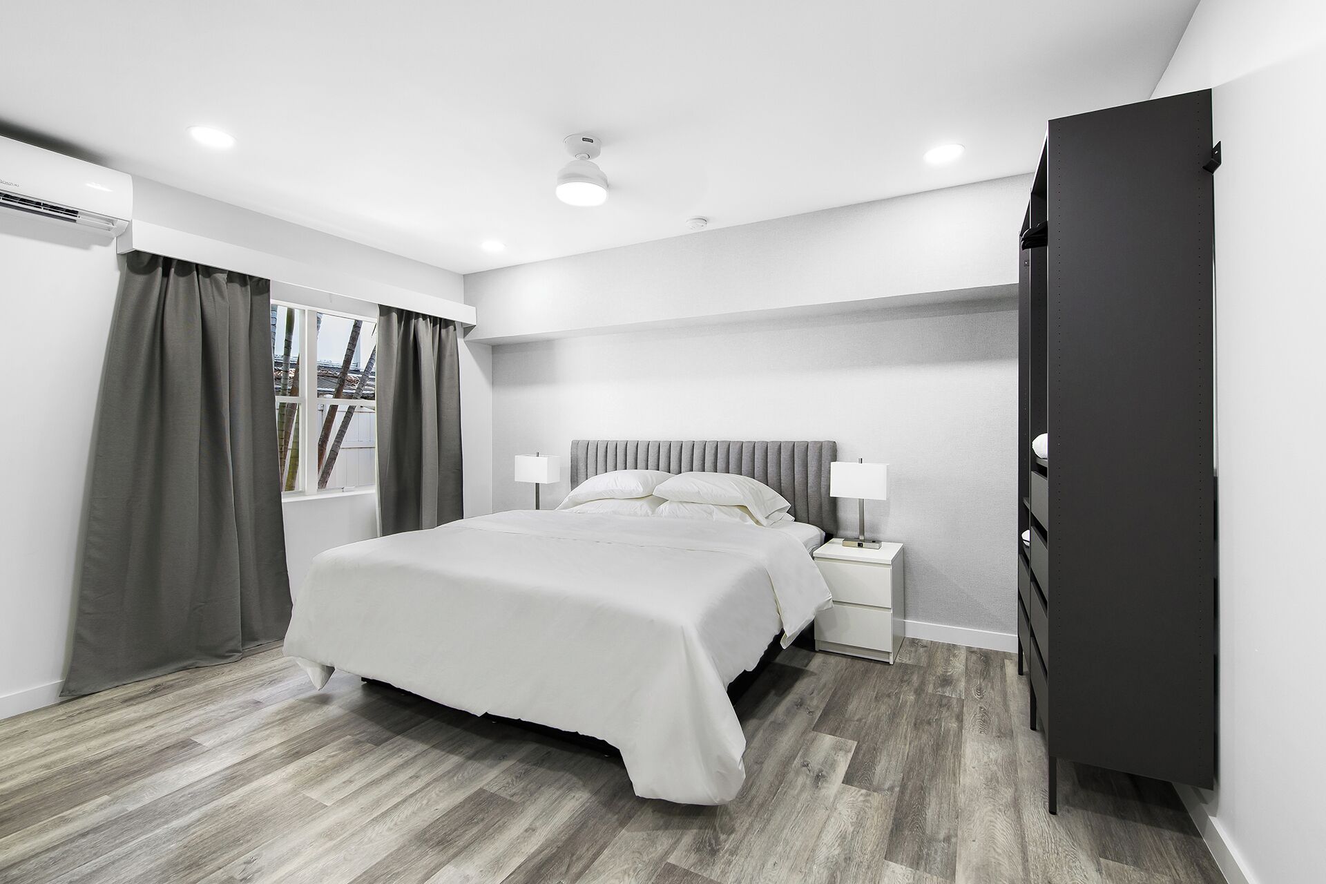 Une chambre moderne avec un grand lit, des lampes de chevet, une armoire et une fenêtre avec des rideaux.