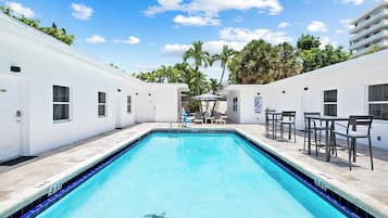 Una piscina al aire libre, sombrillas, sillones reclinables de piscina