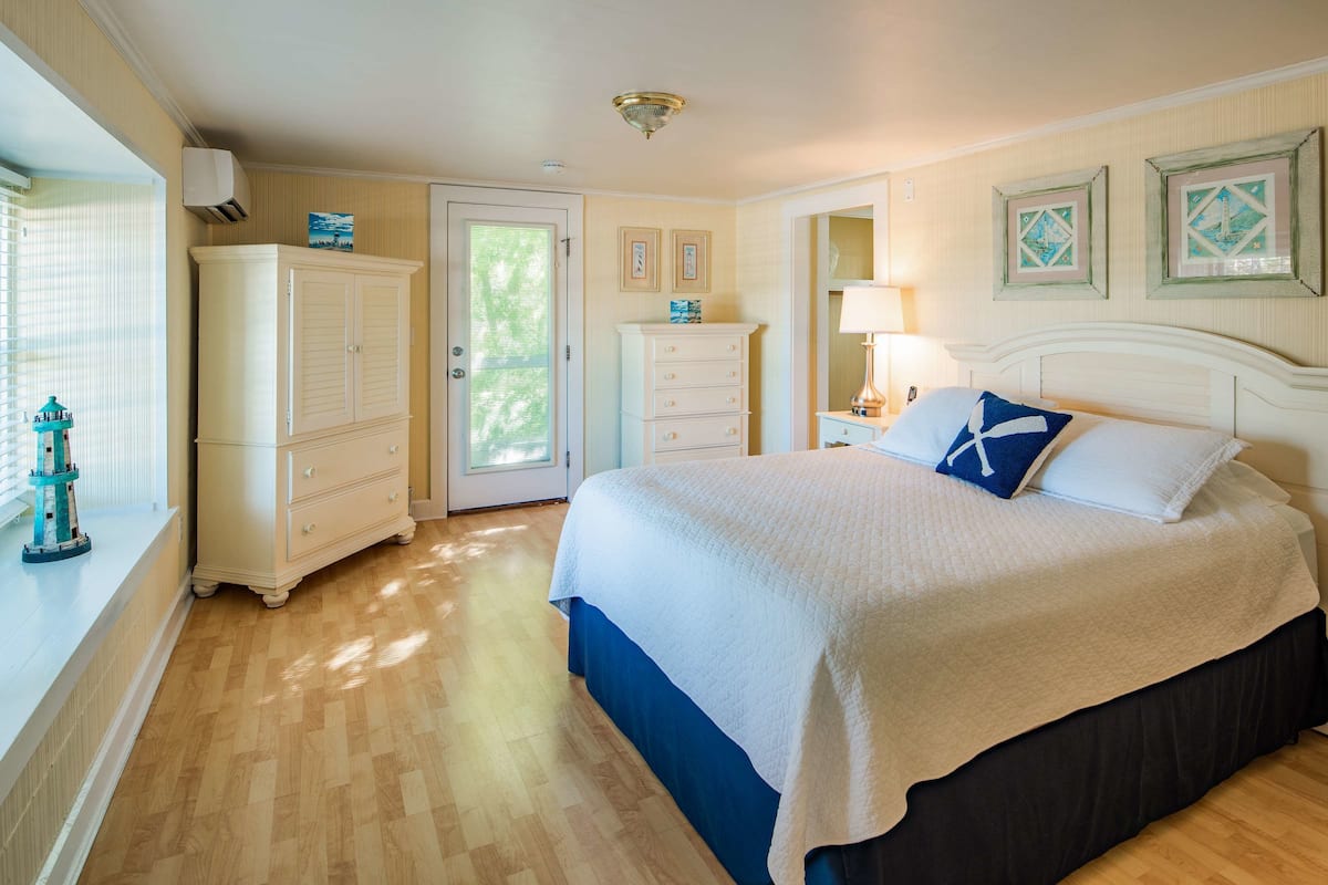 A bedroom with a bed, dresser, and window with blinds.