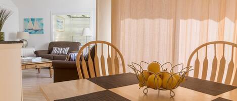 A dining area with a wooden table, two chairs, and a fruit bowl.