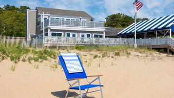 A beach house with a balcony, a flag, and a beach chair.