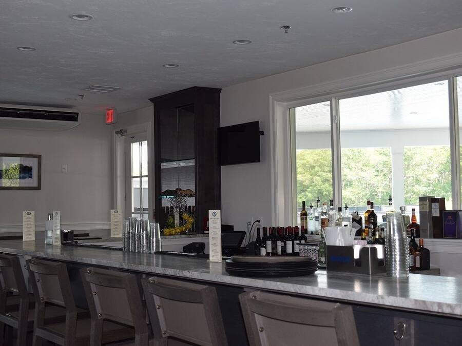 A modern kitchen with a bar area, large windows, and a view of greenery outside.