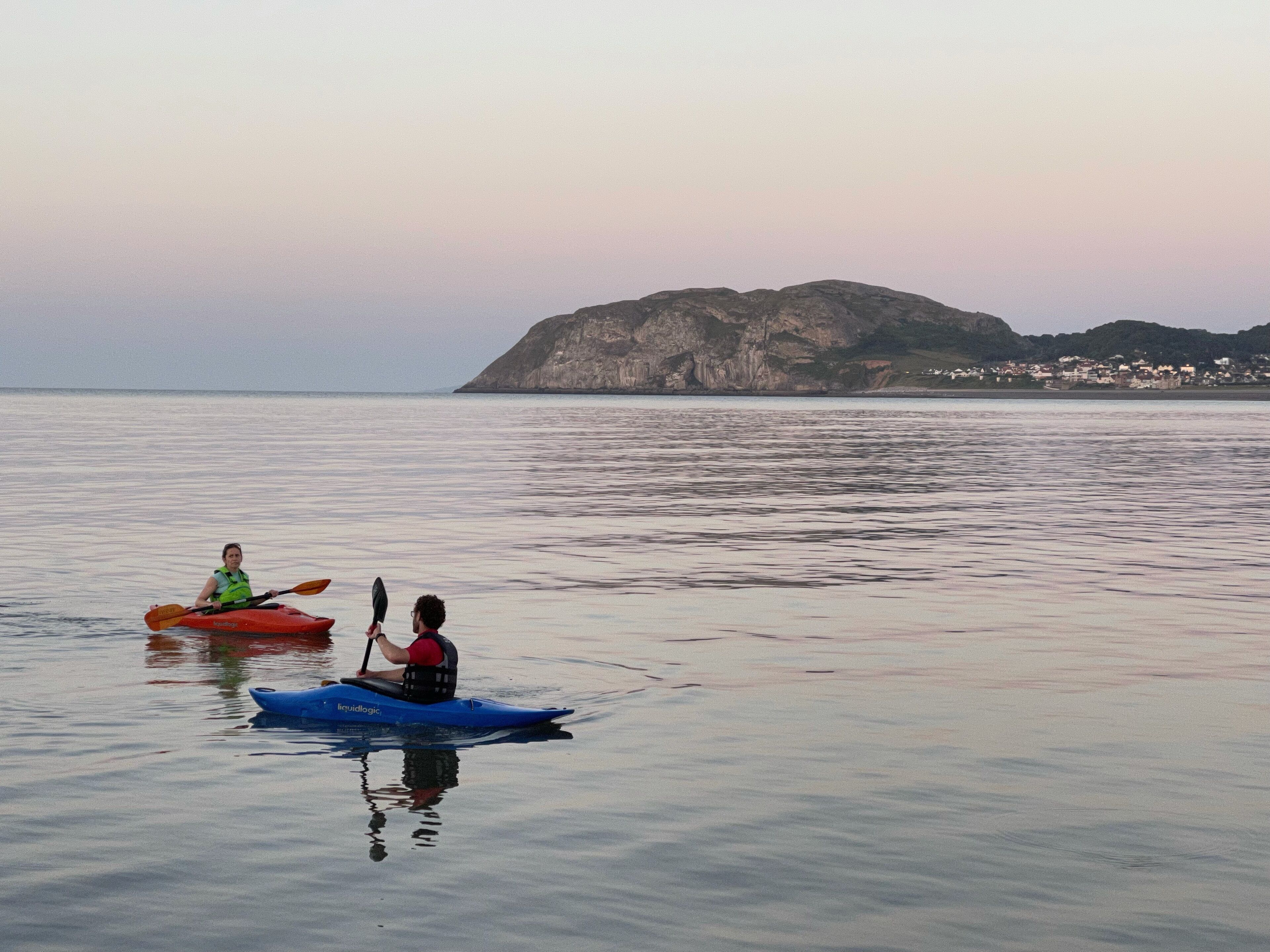 Two kayaks on calm water with a mountainous backdrop.