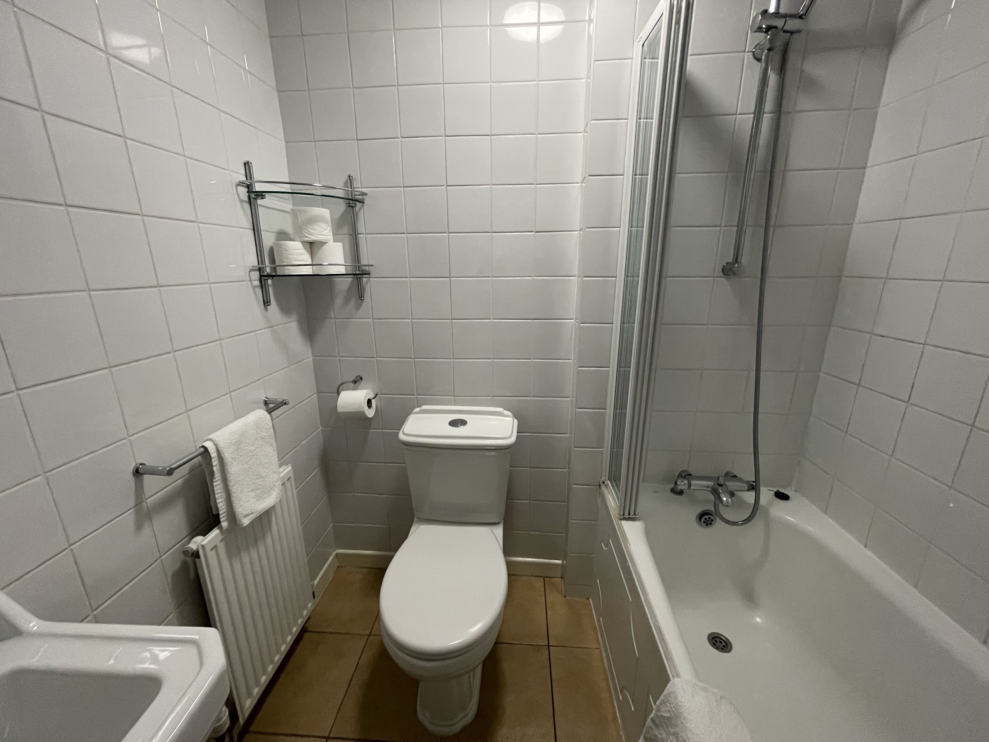 A bathroom with a toilet, a shower, and a sink.