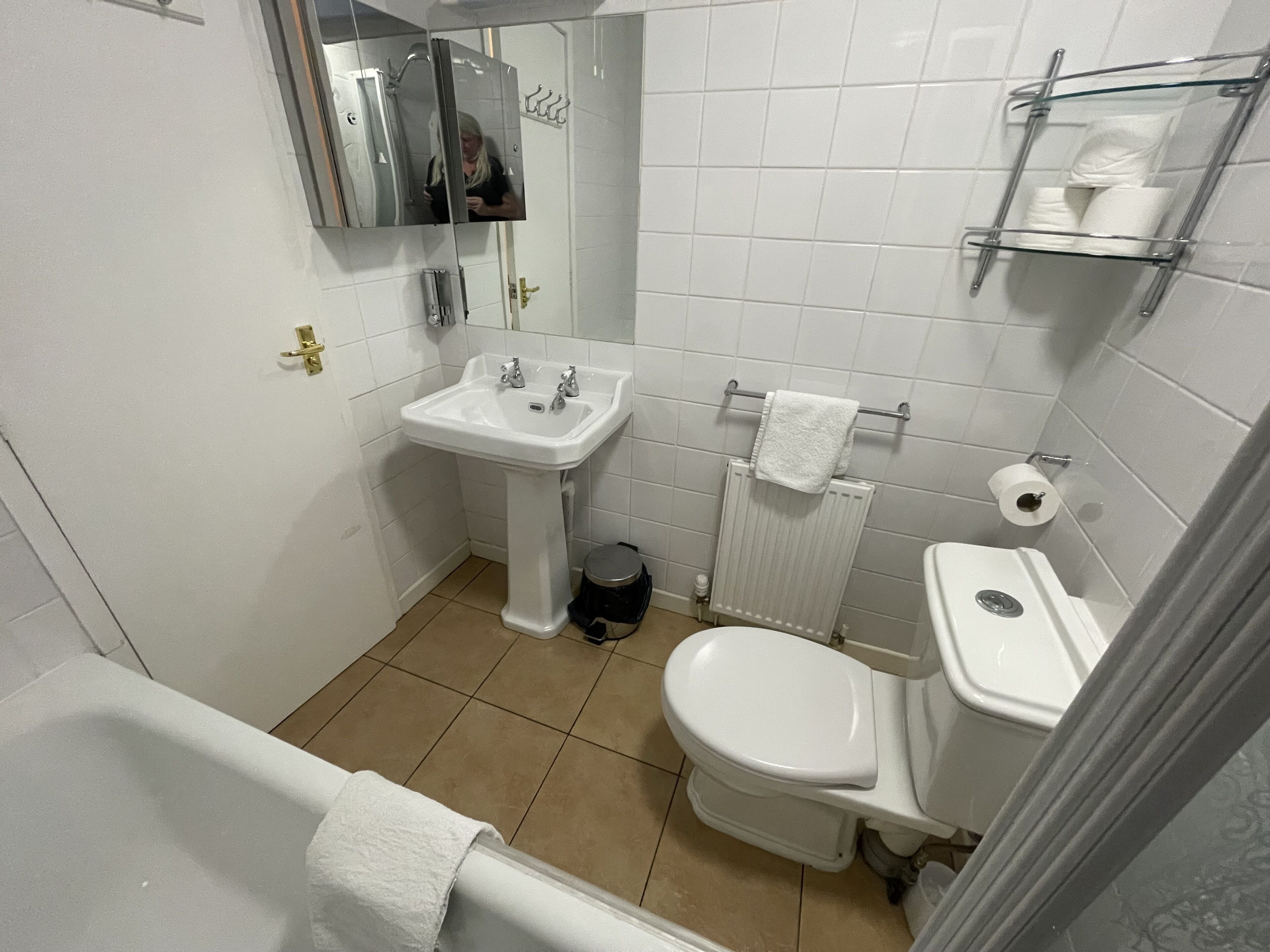 Een badkamer met een wastafel, toilet en spiegel.