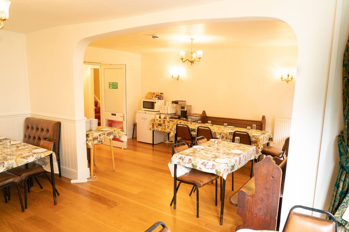 A dining area with multiple tables and chairs, a kitchen area with appliances, and a door marked "Fire Exit".