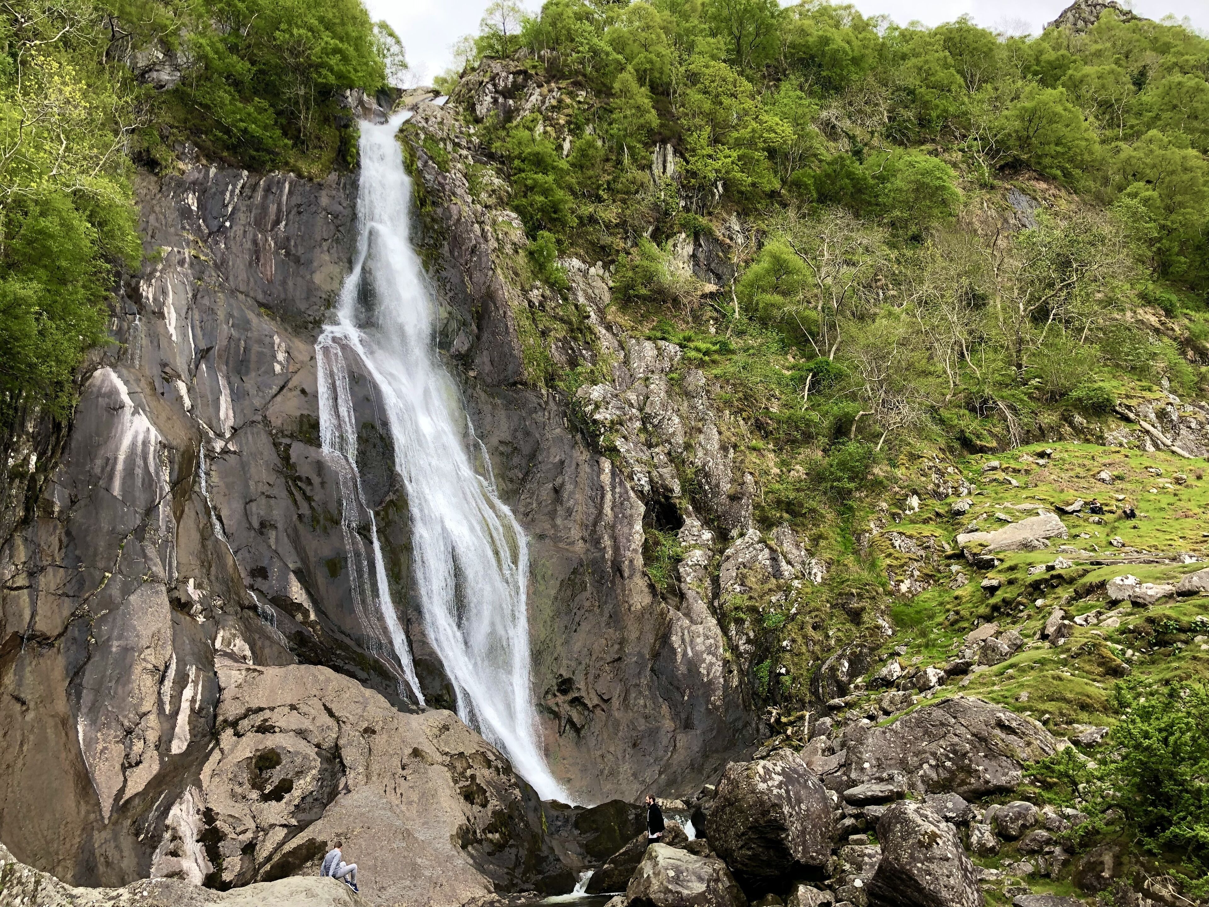 Une cascade se déversant le long d’une falaise rocheuse, entourée d’une végétation luxuriante.