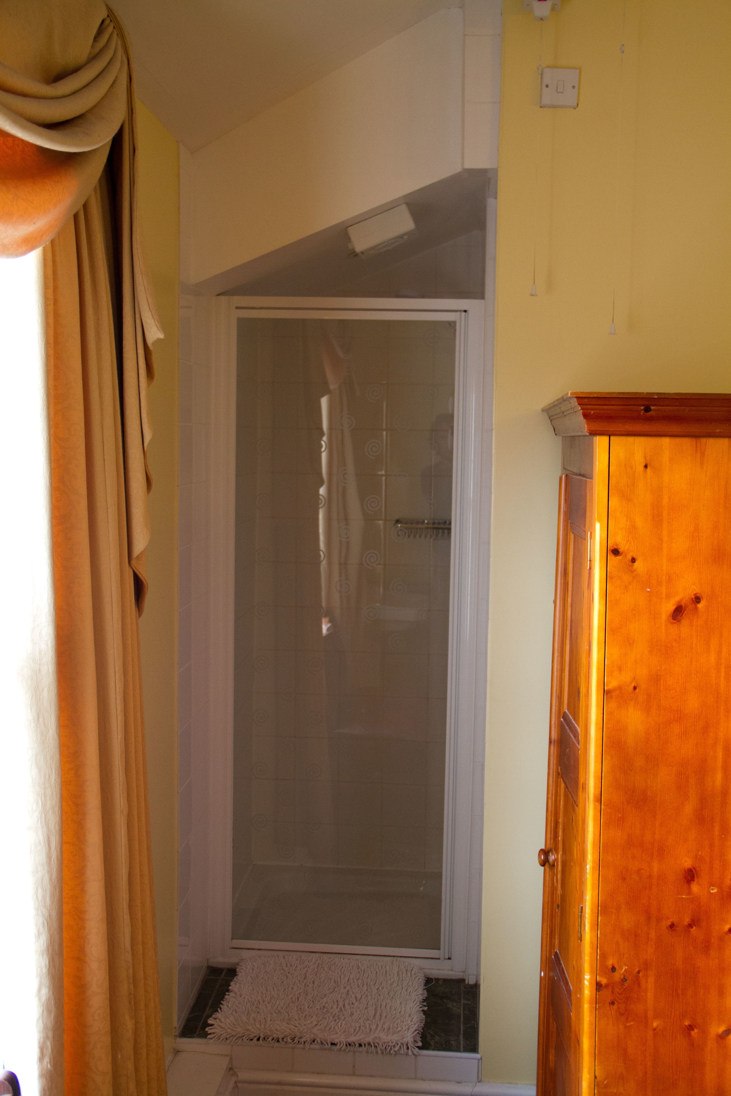 A bathroom with a glass shower enclosure, a wooden cabinet, and a towel rack.