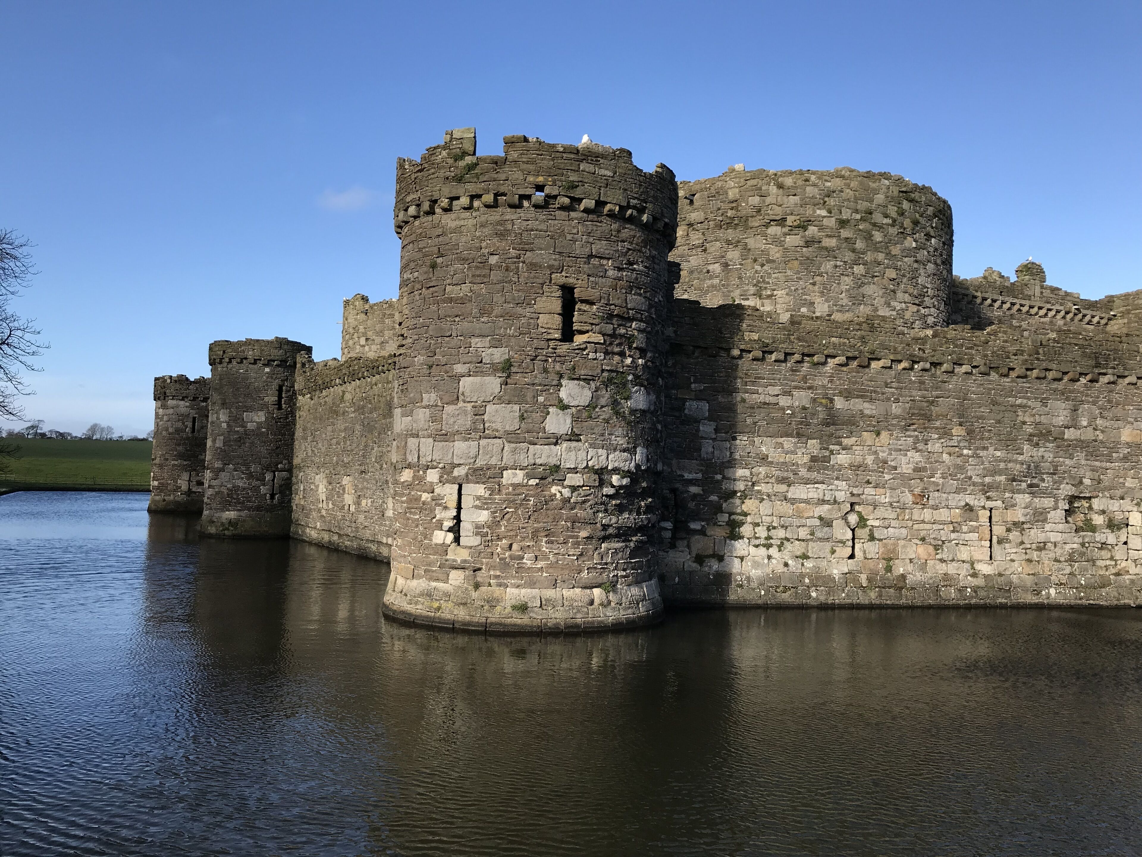 A historic stone castle with a moat, featuring a large central tower and multiple smaller towers.