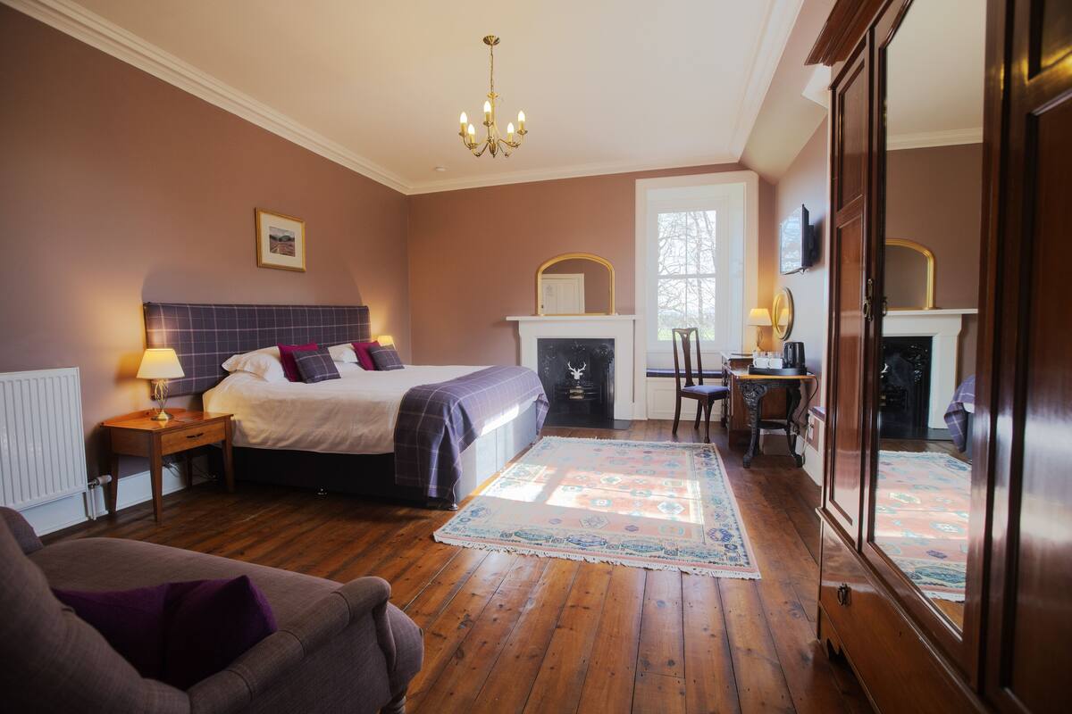 A bedroom with a bed, bedside table, lamp, and a fireplace.