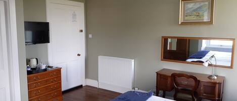 Un dormitorio con cama, cómoda, televisor y espejo.