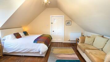 Une chambre à coucher avec un lit, un canapé, un plancher en bois, une porte et un radiateur.