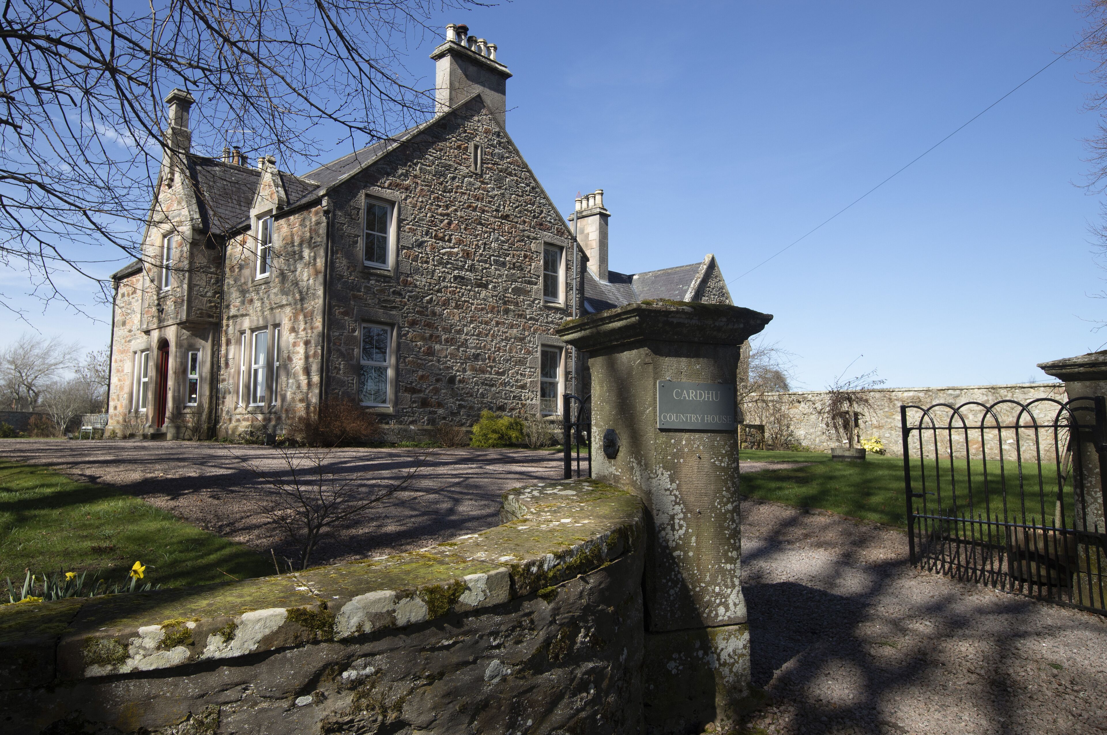 A stone building with a traditional architectural style, featuring multiple windows and a prominent chimney.