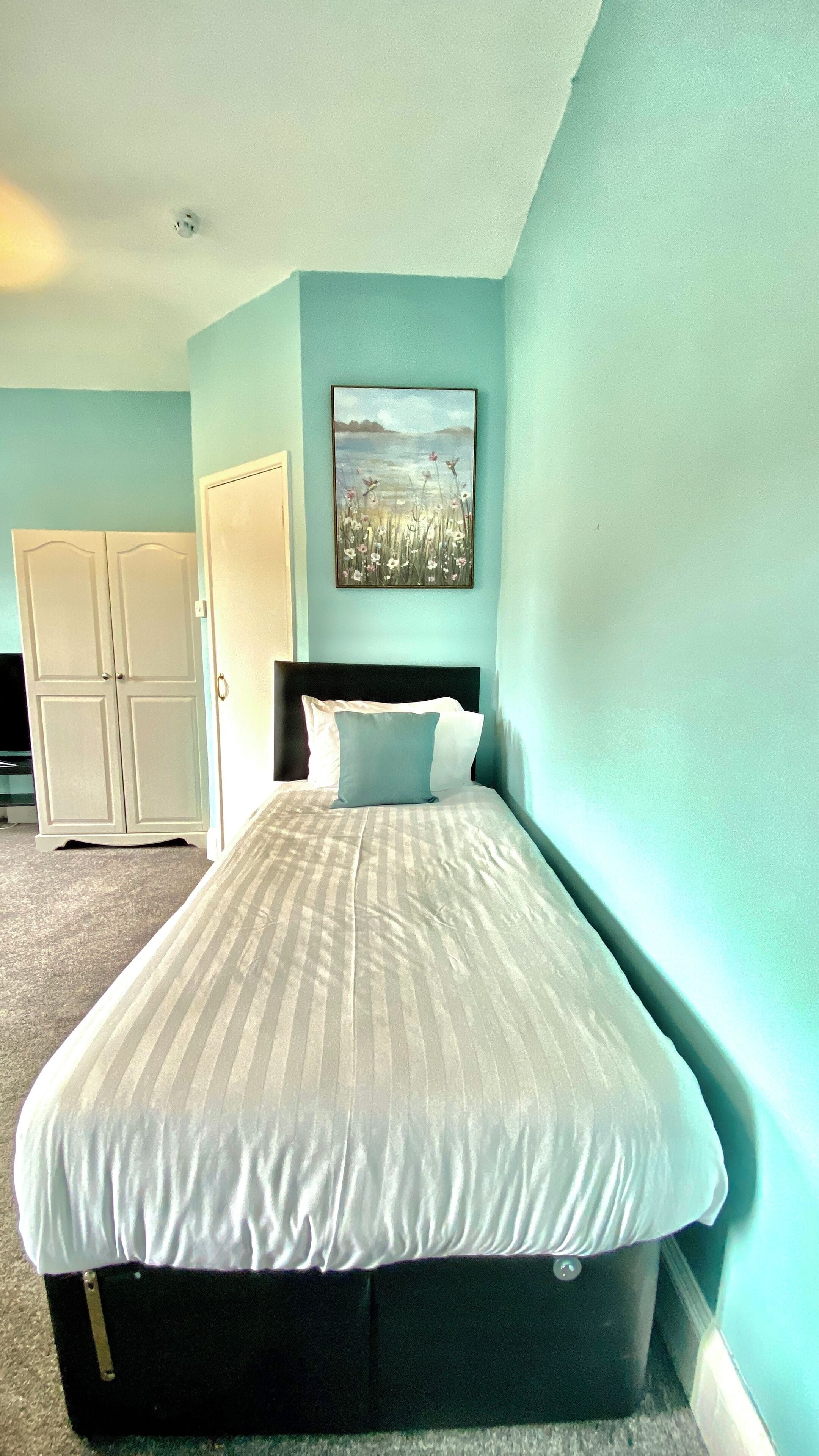 Un dormitorio con cama, un cuadro en la pared y un armario.
