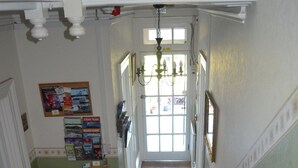 A staircase with a floral carpet, white balusters, and a chandelier. - Tusker Lodge (Torquay)