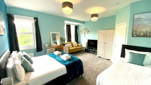 A hotel room with a bed, a sofa, a TV, a wardrobe, and a desk. - Tusker Lodge (Torquay)