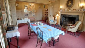 A dining room with a checkered tablecloth, wooden chairs, a fireplace, and framed pictures on the walls. - Kelly House (Lifton)