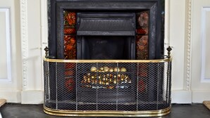 A fireplace with a decorative metal grate and a black surround. - Kelly House (Lifton)