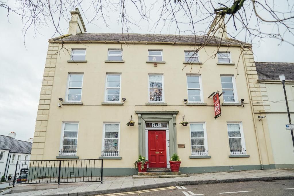 A two-story building with a red door, multiple windows, and a sign indicating a business.