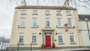 A two-story building with a red door, multiple windows, and a sign indicating a business.