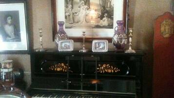 A piano with decorative vases and framed pictures on a stand.