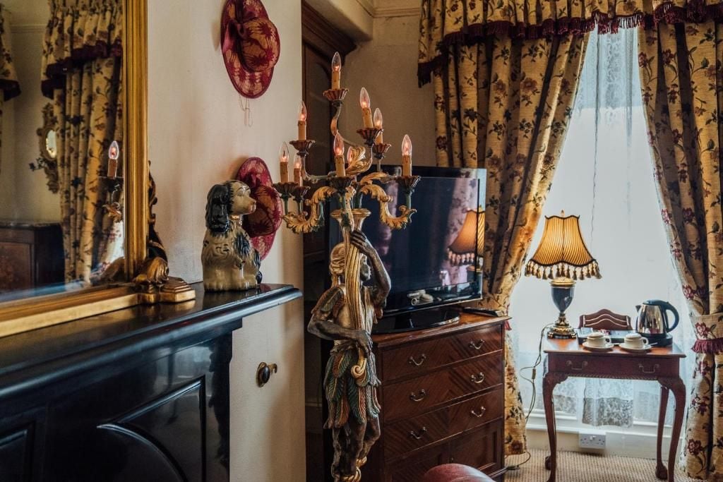 Une pièce avec une télévision, un chandelier décoratif, un miroir et une fenêtre avec des rideaux.