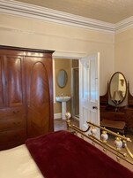 A bedroom with a bed, a wardrobe, a mirror, and a dresser.