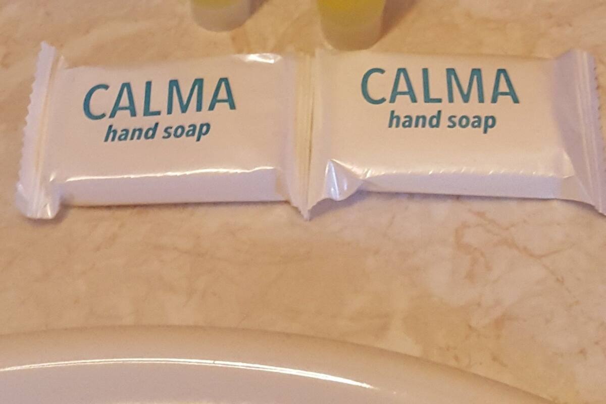 Three hand soap packets and two hand soap containers on a countertop.