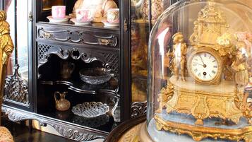 A vintage cabinet with ornate carvings and a glass dome showcasing a golden clock with intricate details.