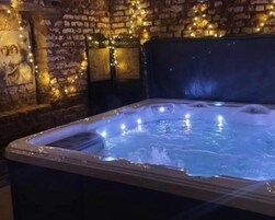 Un jacuzzi con pared de ladrillo y luces colgantes.