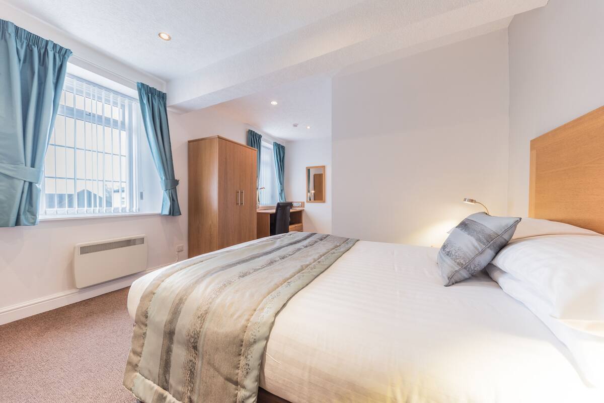 Une chambre à coucher avec un lit, un bureau et une armoire.