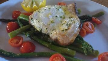 A plate with a piece of fish, asparagus, cherry tomatoes, and a lemon wedge.