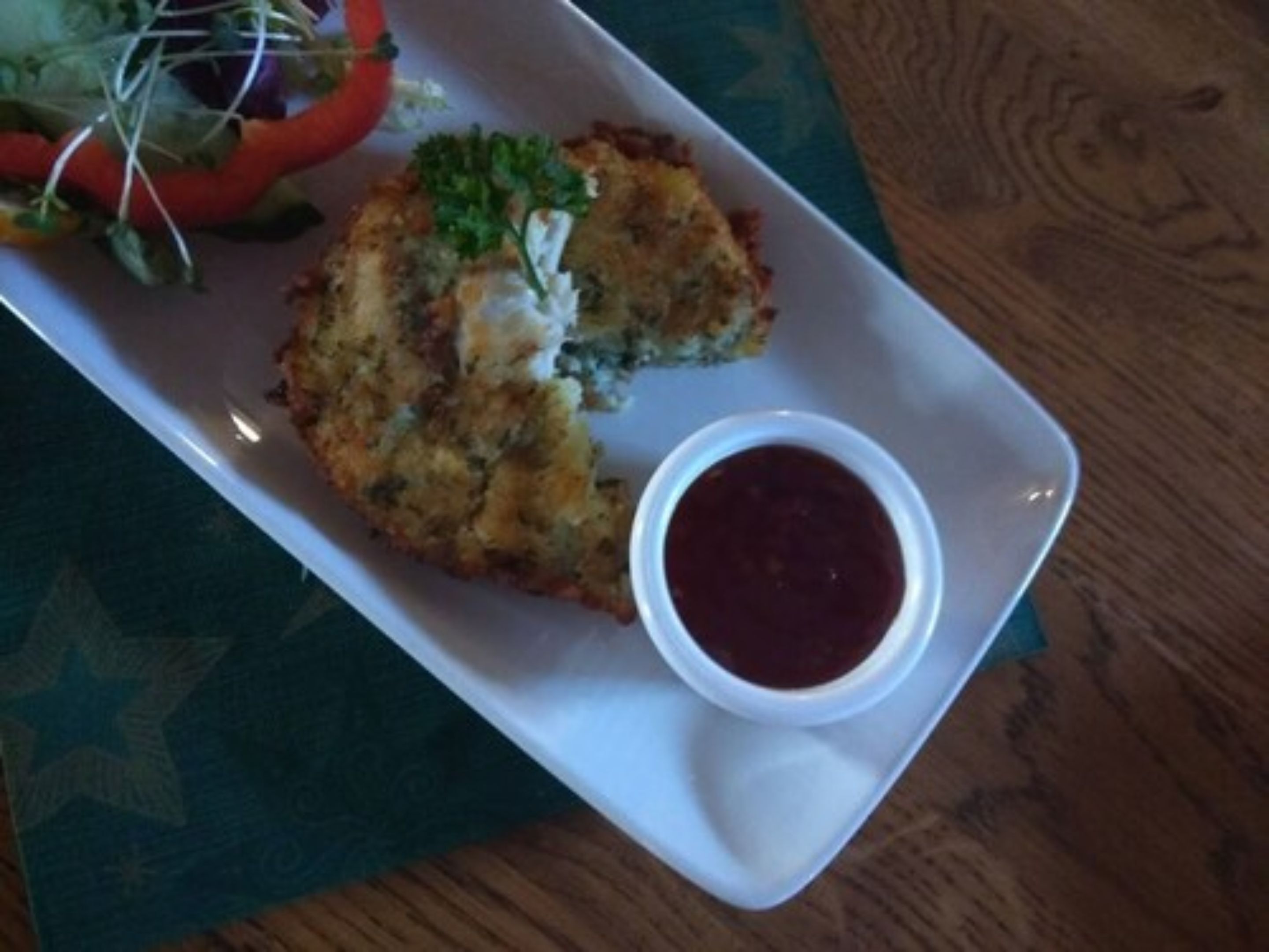 A plate with a food item and a small bowl of sauce.