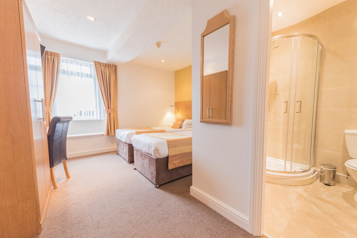 Une chambre d’hôtel équipée d’un lit, d’un bureau, d’une chaise, d’une douche et de toilettes.