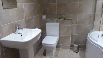 Un baño con lavamanos, inodoro y bañera blancos.