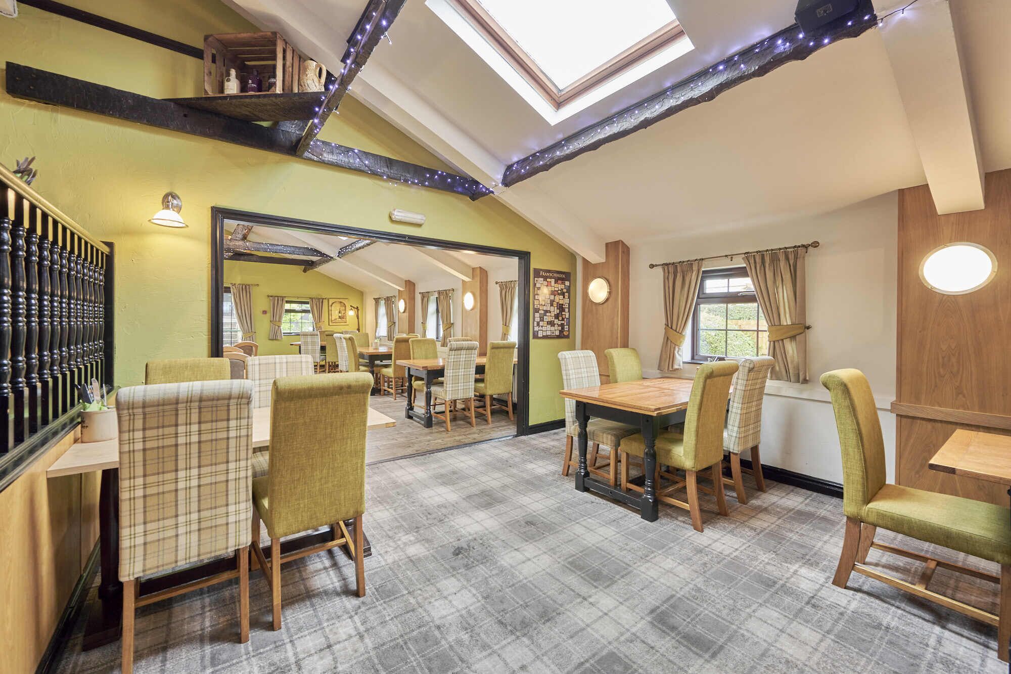 A cozy dining area with a high ceiling, wooden beams, and a checkered floor.