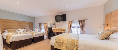 A hotel room with two beds, a desk, a chair, a TV, and a window with curtains.