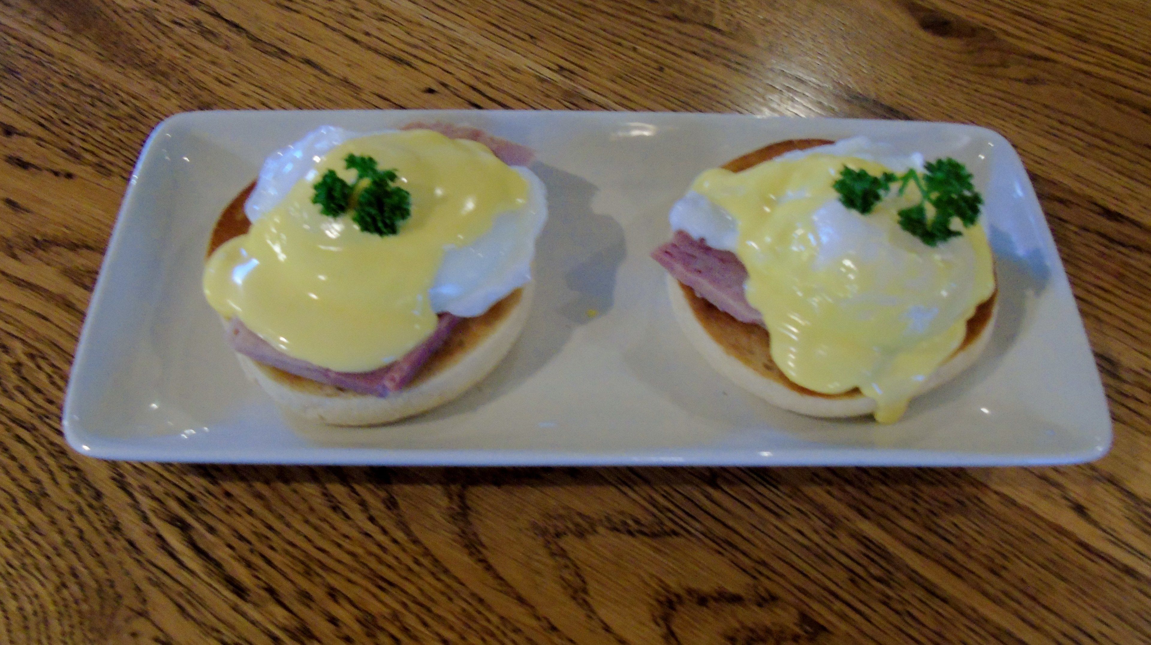 Two eggs benedict dishes on a white rectangular plate.