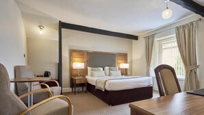 Una habitación de hotel con cama, dos mesitas de noche, un escritorio y una silla.