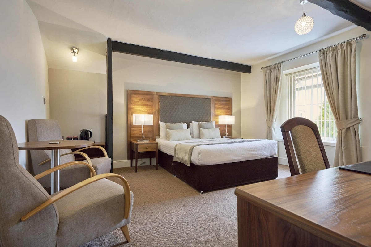 Une chambre d’hôtel comprenant un lit, deux tables de chevet, un bureau et une chaise.