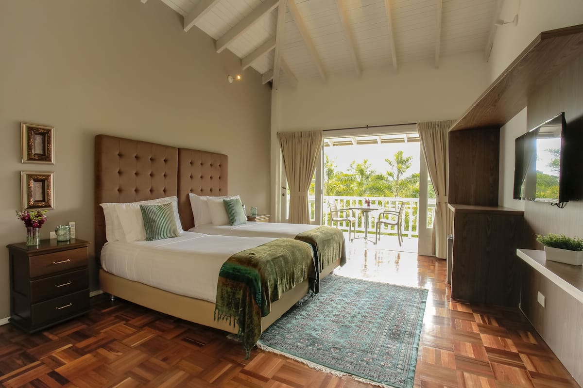 Un dormitorio con una cama grande, televisión, suelo de madera y un balcón con vistas.