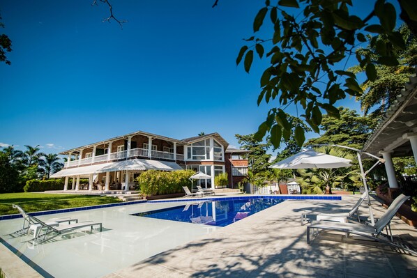 Una piscina al aire libre, sillones reclinables de piscina