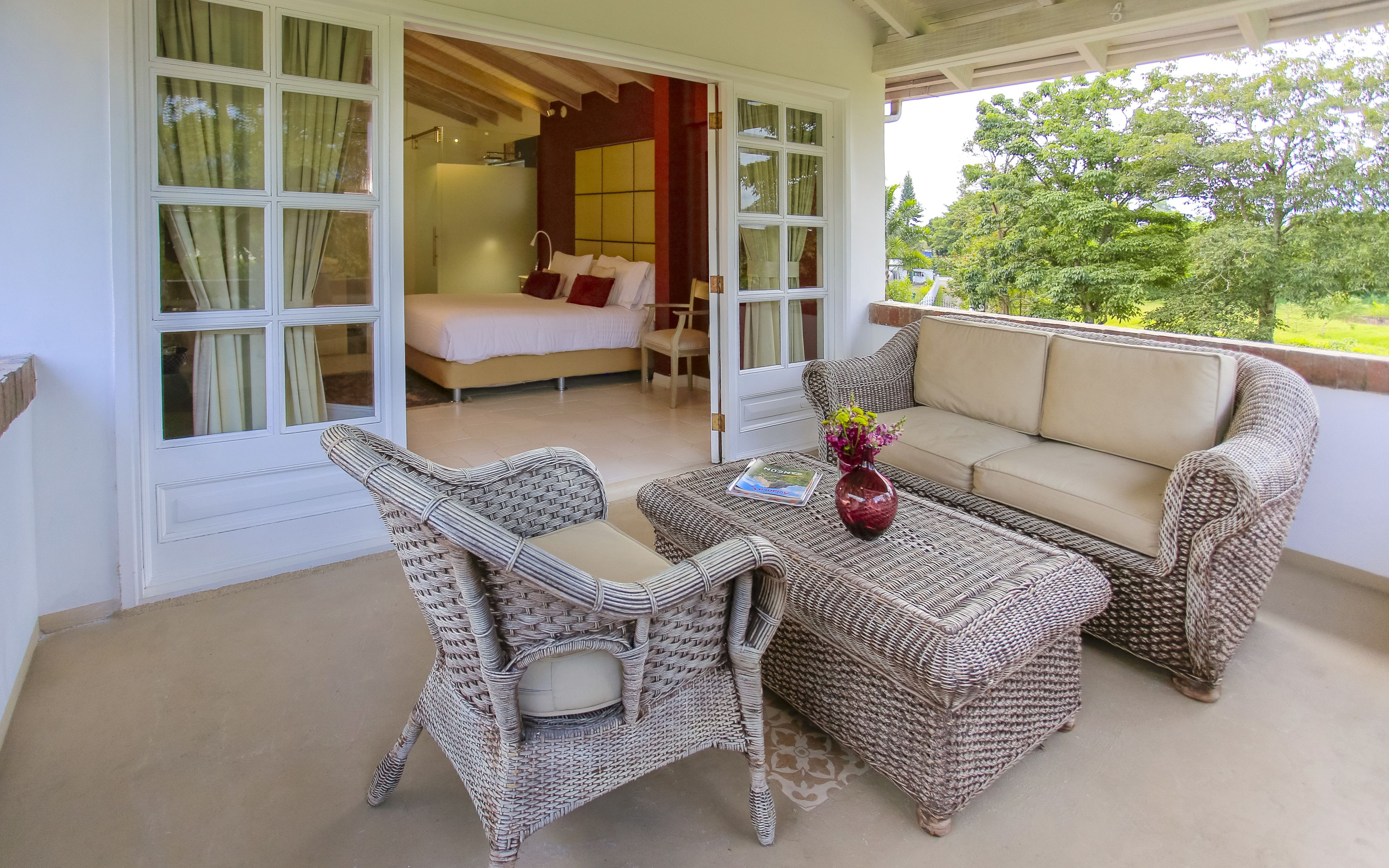 A balcony with wicker furniture, a sofa, and a table with a magazine and flowers.