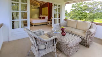 Ein Balkon mit Korbmöbeln, einer Couch und einem Tisch mit Zeitschrift und Blumen.