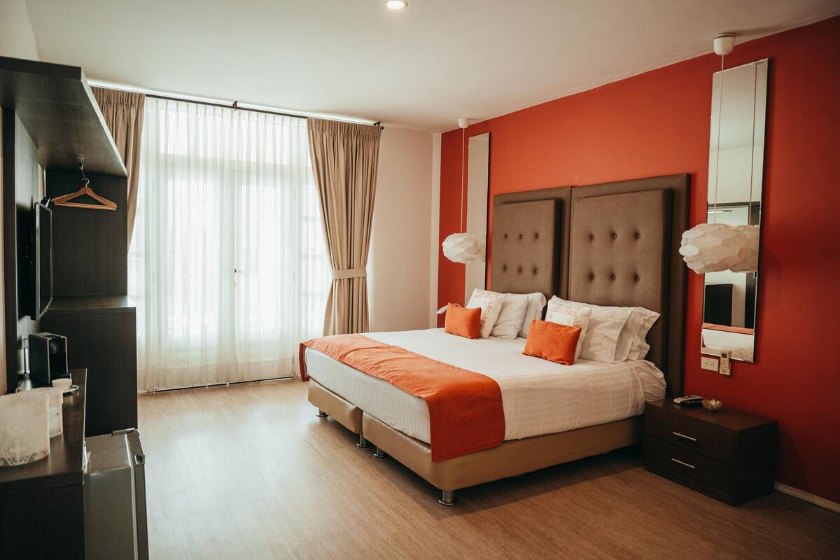 Un dormitorio moderno con una cama grande, un aparador, un espejo y un televisor.