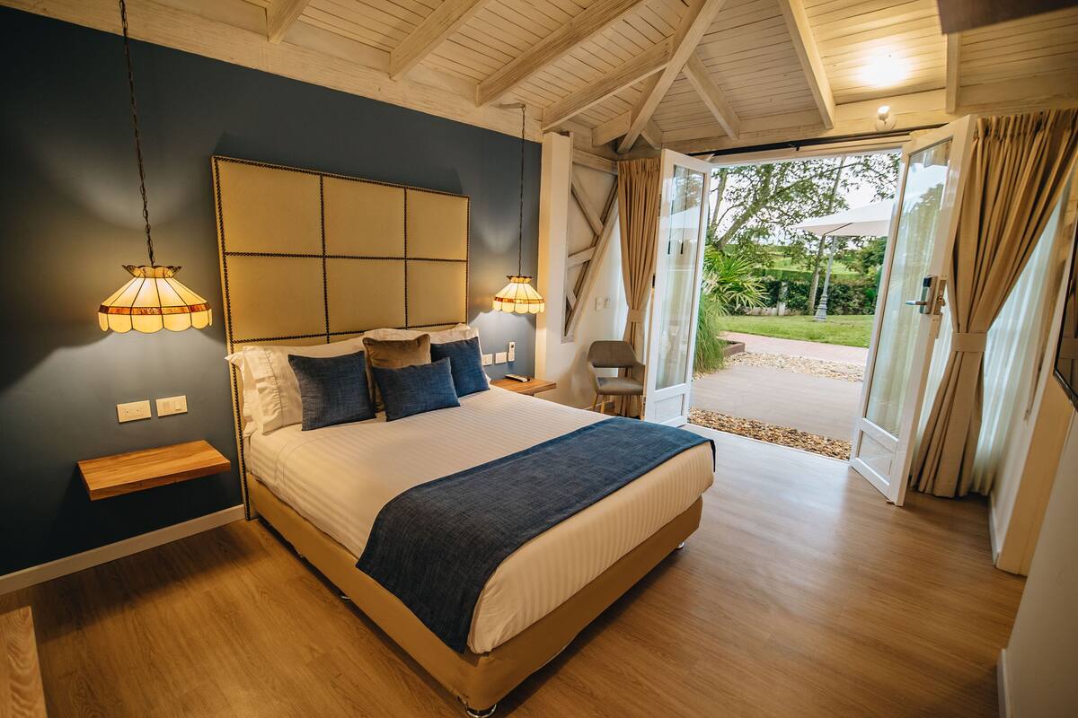 Un dormitorio con una cama grande, mesitas de noche y vistas al exterior a través de una puerta corrediza de cristal.